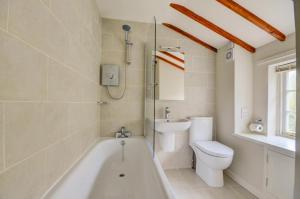 a bathroom with a tub and a toilet and a sink at Aurora Cottage in Little Barningham +10 photos