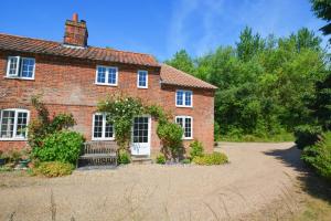 a brick house with a driveway in front of it at Aurora Cottage in Little Barningham