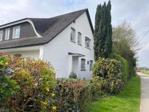 a white house with a black roof and some bushes at Idyllische Wohnung mit Weitblick in Neukirchen-Vluyn
