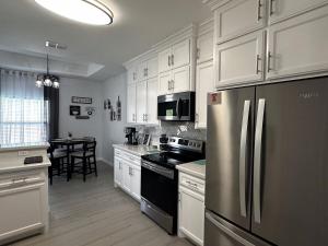 a kitchen with white cabinets and a stainless steel refrigerator at Quiet Cozy Spacious Stay w Private Pool in Brownsville