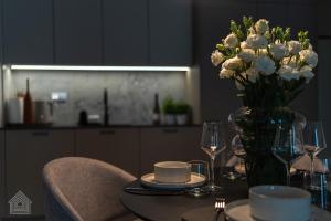 a dining room table with a vase of white flowers at Grzybowska Luxury Apartment with Skyline View by House Expert Warsaw in Warsaw
