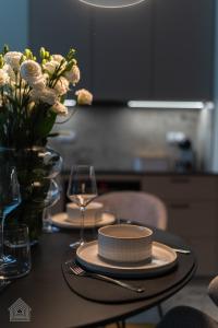 a table with plates and glasses and a vase of flowers at Grzybowska Luxury Apartment with Skyline View by House Expert Warsaw in Warsaw