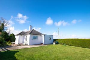a small white house with a grass yard at Bolams Lodge in Ancroft