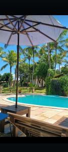a table with an umbrella next to a swimming pool at Porto do Sol - Chalé 25 in Pipa