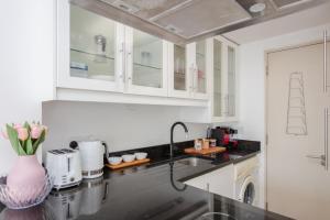 a kitchen with white cabinets and a black counter top at Stylish 1 Bedroom Apartment Near Northcote Road in London