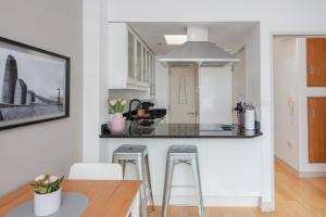 a kitchen with a counter and stools in a room at Stylish 1 Bedroom Apartment Near Northcote Road in London