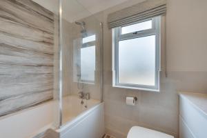 a bathroom with a tub and a toilet and a window at Briargate 38 in Burnham Market +5 photos