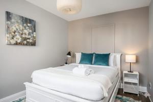 a white bedroom with a large white bed with blue pillows at Limited Time Offer Downtown Stay Parking in Atlanta +13 photos