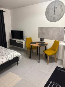 Habitación con mesa, sillas y reloj en la pared en Apartament Słowackiego Park, en Zabrze