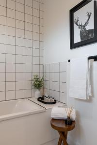 baño con bañera y pared de azulejos blancos en Botanic House - 3BR Home - Private Parking, en Glasgow