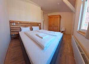 a bedroom with a large white bed with a wooden headboard at albgut GmbH - Übernachten im Kulturdenkmal Altes Lager Hotel BT7 und BT9 in Münsingen +4 photos
