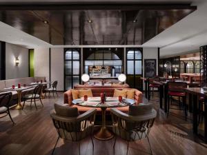 Un restaurante con un sofá, mesas y sillas. en Pullman Bandung Grand Central, en Bandung