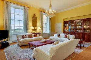 a living room with white furniture and a chandelier at The East Wing at Wolterton Hall in Itteringham