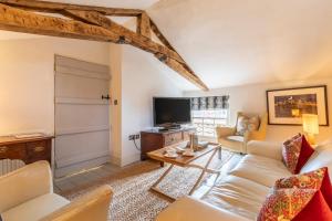 Una sala de estar con un sofá y un televisor. en The Stewards House at Wolterton Hall, en Itteringham