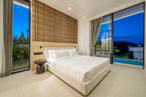 a bedroom with a white bed and large windows at Ardhana 12 - Spacious and Stylish Villa - Pool - Full Kitchen - Netflix in Ungasan