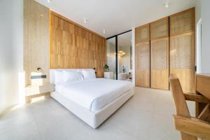 a bedroom with a white bed and wooden walls at Ardhana 12 - Spacious and Stylish Villa - Pool - Full Kitchen - Netflix in Ungasan