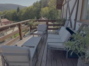 a porch with two chairs and a couch on a deck at AmurguluiBnB 3-Bedroom Bucegi Mountains Retreat in Buşteni