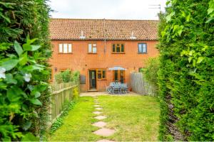 a brick house with a garden and a patio at 2 Mallard Cottages in Tattersett
