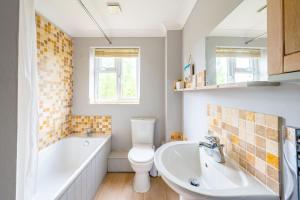 a bathroom with a tub and a toilet and a sink at 2 Mallard Cottages in Tattersett +23 photos