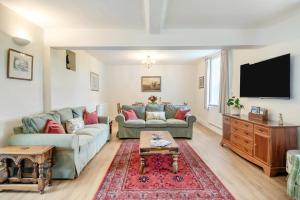 a living room with two couches and a flat screen tv at Meadow Farmhouse in Whissonsett