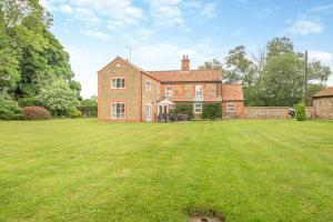 a large brick house with a large grass yard at Meadow Farmhouse in Whissonsett