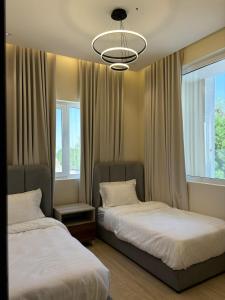 a bedroom with two beds and a chandelier at شاليهات الشروق Sun Shine Chalets in Dhahran +33 photos