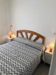 ein Schlafzimmer mit einem Bett mit einer schwarz-weißen Bettdecke in der Unterkunft Apartament 3 habitacions i espectaculars vistes al mar in Llança