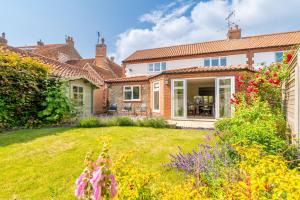 une maison avec une cour ornée de fleurs et de plantes dans l'établissement Creake Cottage, à Burnham Market