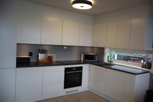 een keuken met witte kasten en een zwart apparaat bij Modern apartment on Kvaløya in Tromsø