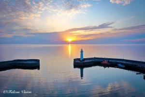 a lighthouse in the middle of the water with the sunset at Double Room in Luxury High Trees Development in Donaghadee