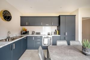 a kitchen with blue cabinets and a table and a clock at Double Room in Luxury High Trees Development in Donaghadee