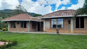 a small brick house with a grass yard at Hermosa Casa de campo cerca a Yolombo, las partidas in Yolombó