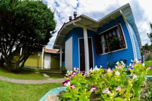 a blue house with flowers in the yard at Pousada Gramadense in Gramado