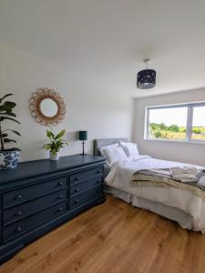 a bedroom with a bed and a dresser with a mirror at Large house 10 min walk to beautiful Wexford Beach 