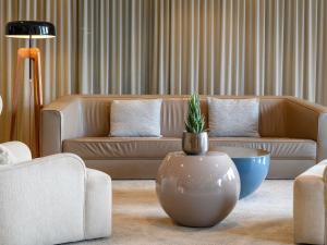 a living room with a couch and a potted plant at Mövenpick Hotel Lausanne in Lausanne