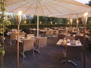 a restaurant with tables and chairs and an umbrella at Mövenpick Hotel Zurich Airport in Glattbrugg