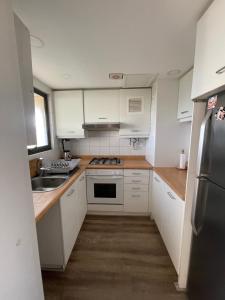 Una cocina con gabinetes blancos y un refrigerador de acero inoxidable. en San Alfonso Del Mar, Algarrobo, en Algarrobo