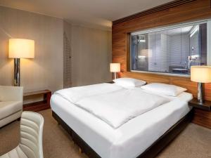 a large white bed in a room with a window at MÖVENPICK Hotel Hamburg City in Hamburg +207 photos