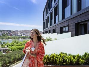 une femme en robe rouge tenant une tasse de café dans l'établissement Mövenpick Istanbul Hotel Golden Horn, à Istanbul
