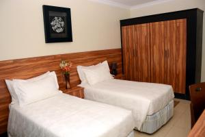 a hotel room with two beds and a wooden door at La Posh Hotel in Kigali