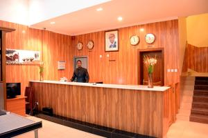 a man standing at a reception counter in at La Posh Hotel in Kigali