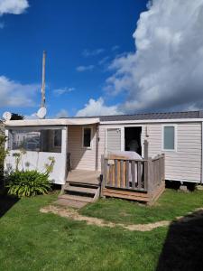 a mobile home with a porch and a fence at mobil-home bord de plage in Sarzeau