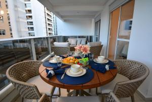a table on a balcony with chairs and food on it at Boulevard Praia de Palmas a 400m do Mar - GCR009 in Governador Celso Ramos