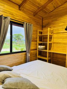 a bedroom with a bed in a wooden room with a window at Refugio del Ocaso - neues Teak-Haus mit Garten in Hojancha