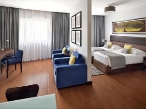 ein Hotelzimmer mit einem Bett und einer blauen Couch in der Unterkunft Mövenpick Hotel Apartments Al Mamzar Dubai in Dubai