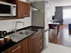 a kitchen with a sink and a microwave at Mövenpick Hotel Apartments Al Mamzar Dubai in Dubai
