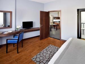 a room with a bed and a desk with a television at Mövenpick Hotel Apartments Al Mamzar Dubai in Dubai +116 photos