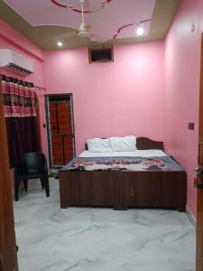 una camera da letto con un letto e una parete rosa di Chandrika Palace Agnikund Near RAM MANDIR a Ayodhya