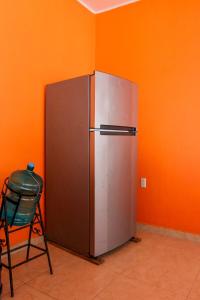 un réfrigérateur argenté dans une pièce avec un mur orange dans l'établissement Casa Playa Blanca, a private beach home, à Ixtapa-Zihuatanejo International