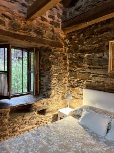 a bedroom with a stone wall with a bed and a window at Casa Folibar in Manzanedo de Valdueza +22 photos